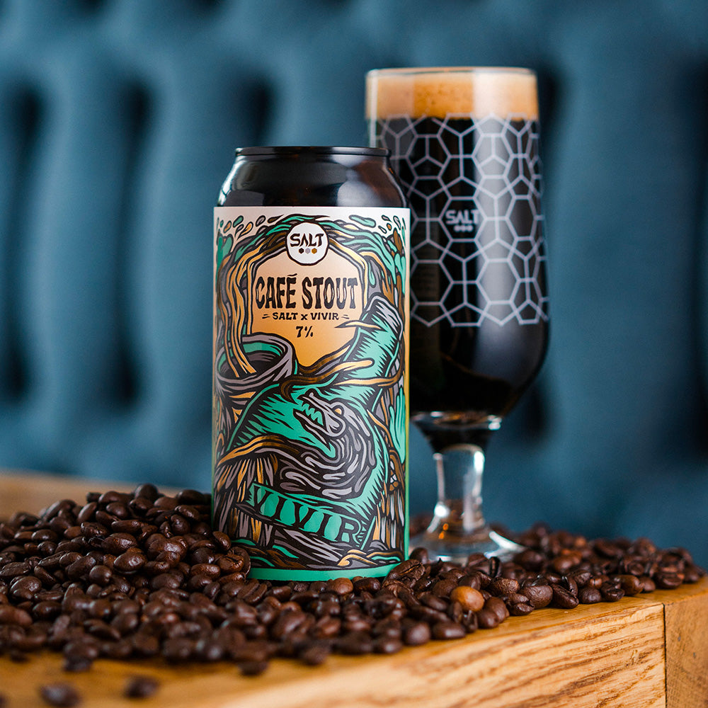 A can of Café Stout next to a glass containing stout infused with VIVIR Café VS and surrounded by coffee beans