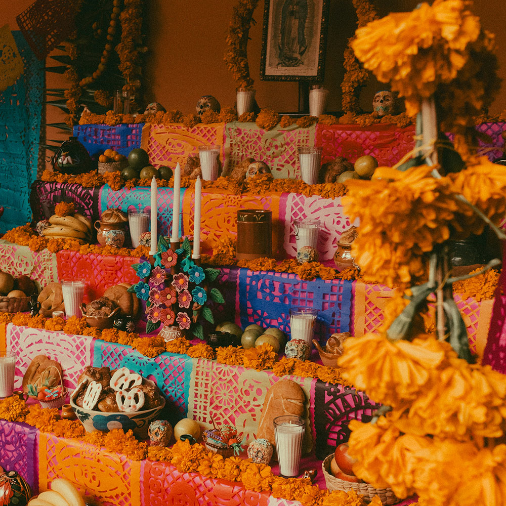 A shrine for the festival of remembrance Day of the Dead, featuring orange Mexican marigold flowers, food and Tequila